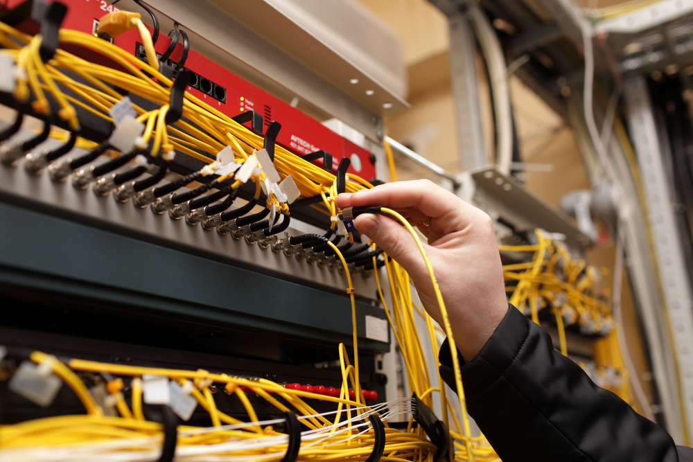 Technician plugging in fiber optic cable to a transceiver